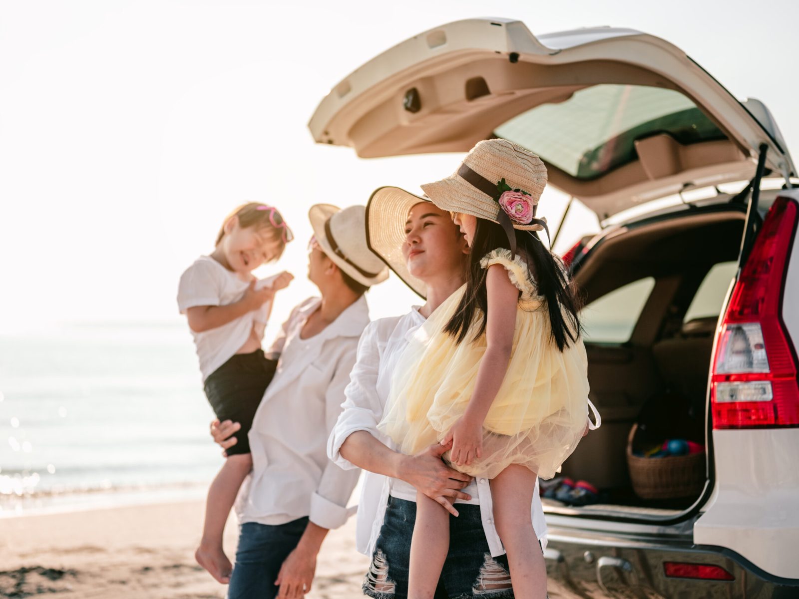 Happy asian family on a road trip in their car. Dad, mom and daughter are traveling by the sea.Parents holding their children.Summer ride by automobile.